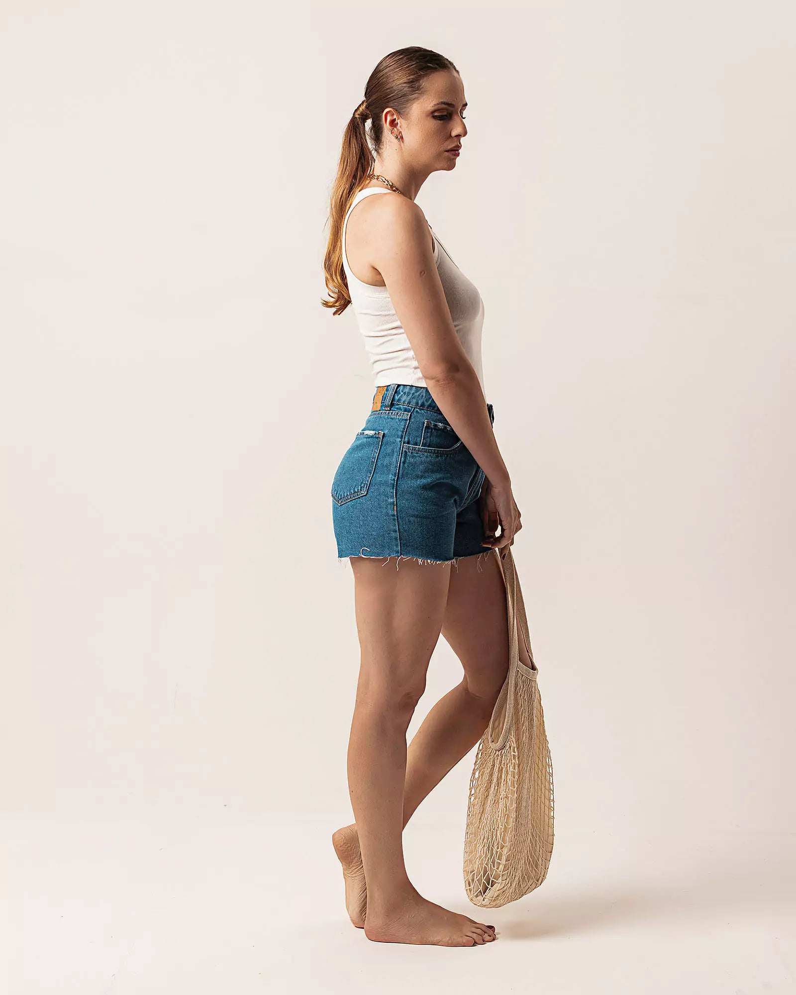 Short Curto Barra Desfiada Jeans Médio Claro Eco Denim™. Compre online moda sustentável e atemporal na Minimadeia. Roupas femininas estilosas, básicas e sustentáveis. Foto produto 04